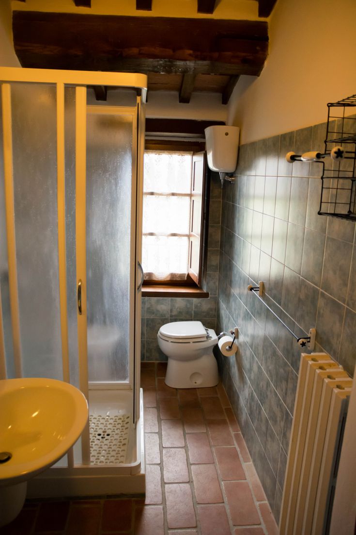 Une salle de bain simple et bien entretenue dans un agriturisme ombrien, avec des détails fonctionnels et accueillants.