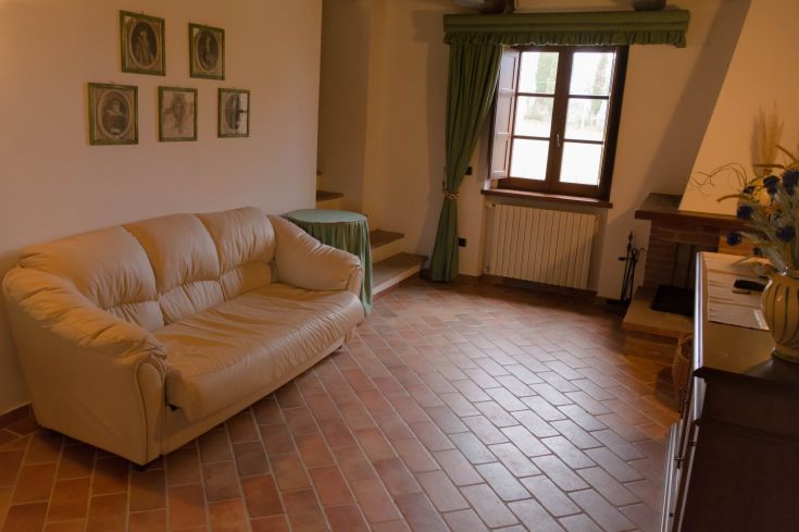 Ambiance chaleureuse d'un agriturisme avec un canapé confortable et des décorations murales simples.