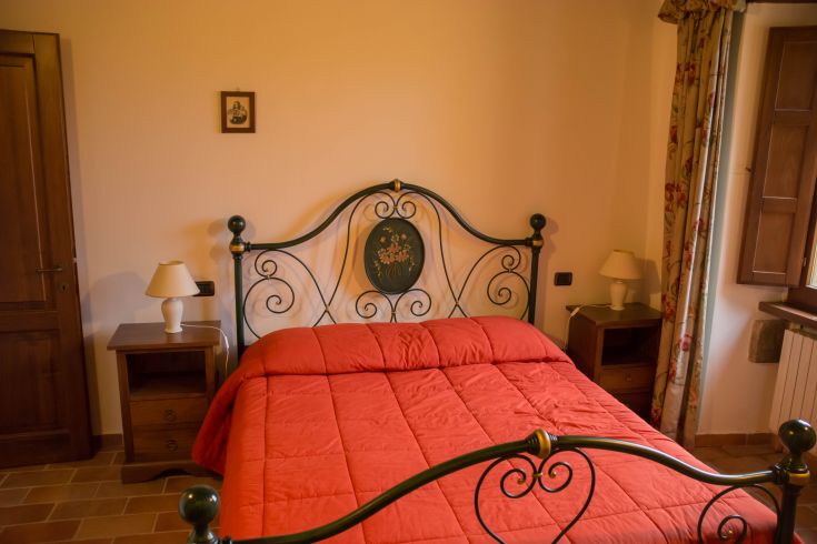 Intérieur d'une chambre d'un agriturismo en Ombrie, équipée d'un lit double et de simples décorations florales.