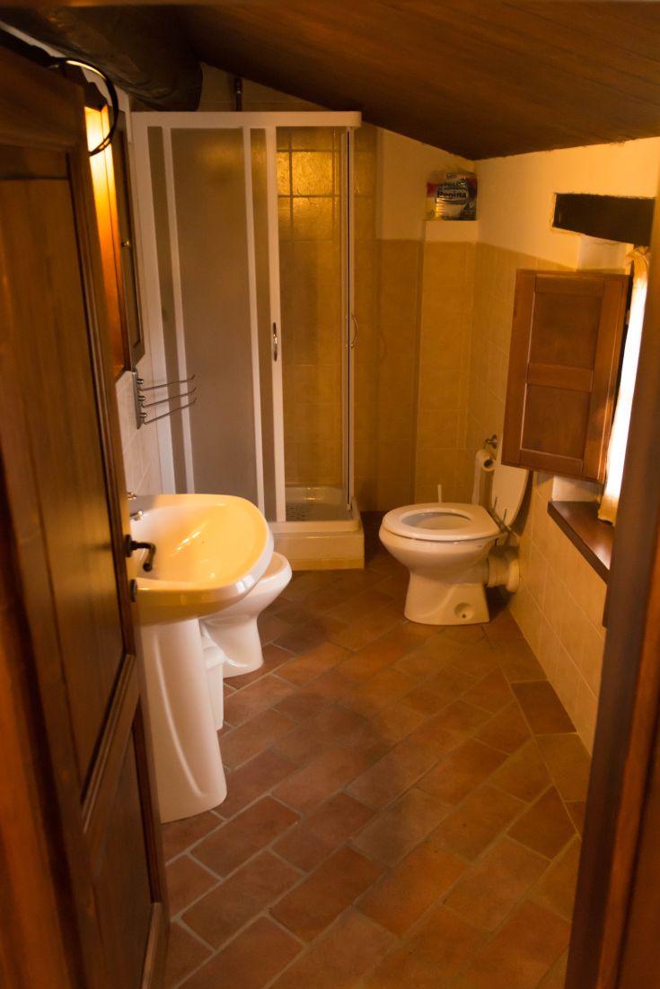 Intérieur d'une ferme en Ombrie avec des carreaux en terre cuite et une douche fonctionnelle.