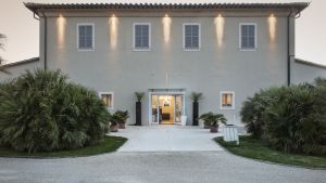 Fassade eines eleganten Gebäudes, umgeben von grünen Pflanzen und einem beleuchteten Weg.