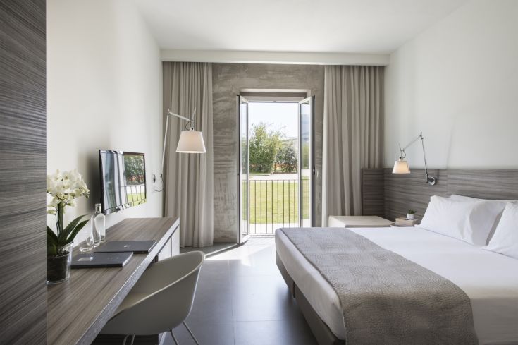 Ein gemütliches Hotelzimmer geschmackvoll eingerichtet, mit einem Fenster, das auf einen gepflegten Garten blickt, ideal für einen ruhigen Aufenthalt.