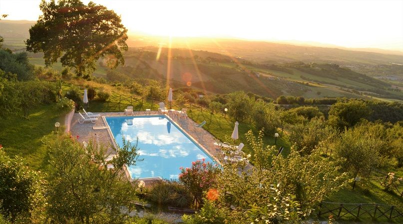 Der Pool, der sich in einem ruhigen Bereich der umbrischen Landschaft befindet, beleuchtet von den Farben des Sonnenuntergangs.
