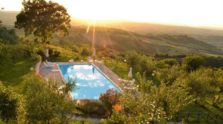 Der Pool, der sich in einem ruhigen Bereich der umbrischen Landschaft befindet, beleuchtet von den Farben des Sonnenuntergangs.