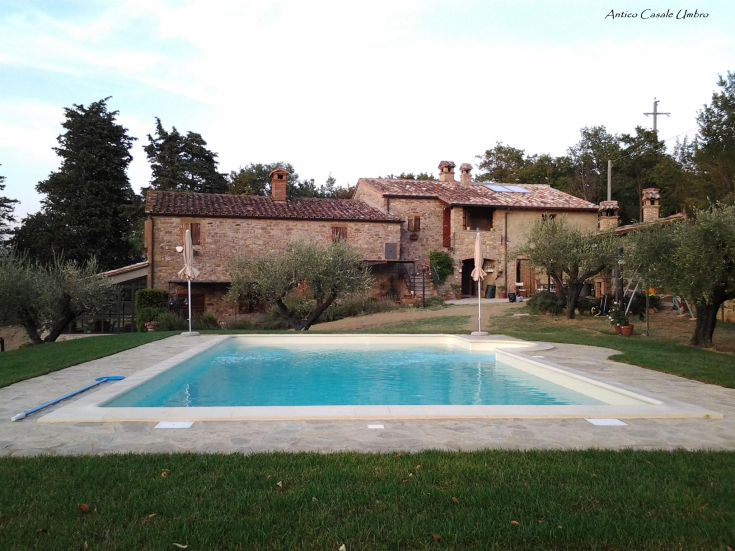 Struttura in pietra con piscina salata, circondata da ulivi, situata vicino al Lago Trasimeno, ideale per momenti di relax.