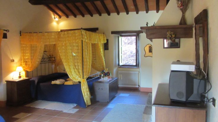 Camera semplice con letto a baldacchino e dettagli gialli. Ambiente tranquillo in un contesto rurale.