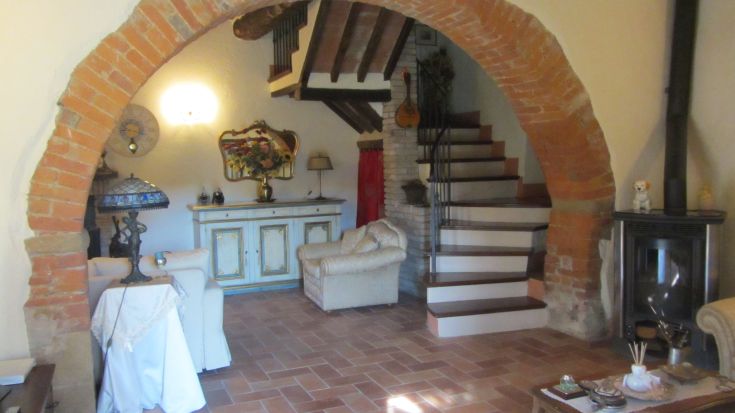 Un'area living gradevole con un architrave in mattoni e scale che portano ai piani superiori.