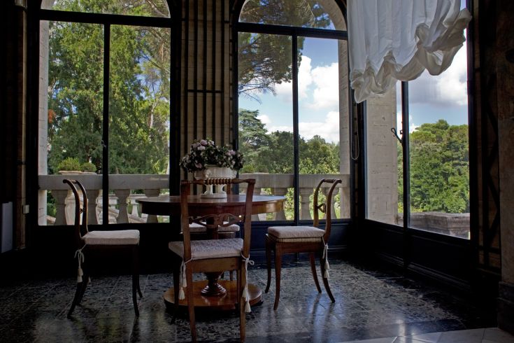 Intérieur simple avec une table et des chaises, vue sur les arbres et les collines environnantes.