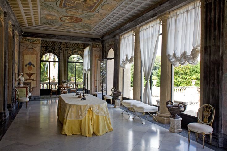 Intérieur d'une villa avec de grandes fenêtres laissant entrer la lumière naturelle et un mobilier épuré.