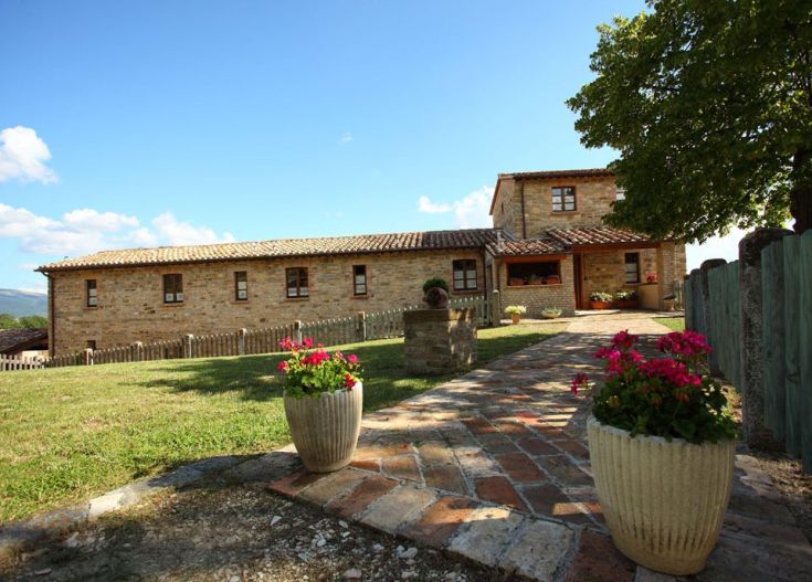 Diese ländliche Struktur befindet sich in der umbrischen Landschaft, umgeben von Vegetation und verschiedenen Blumen.