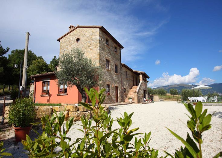 Eine einfache Farm im umbrischen Landschaft, umgeben von grünen Flächen.