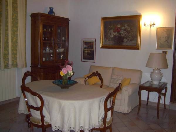 Soggiorno semplice con tavolo e divano, arredato con mobili tradizionali.