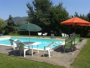 Una piscina di grandi dimensioni immersa in un'area verde attrezzata con ombrelloni e lettini.