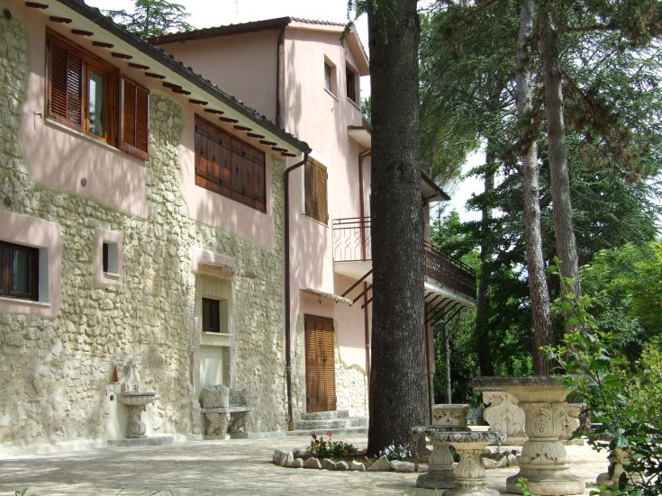 Edificio in parte in pietra circondato da un ampio giardino, piscina e accesso diretto al lago.