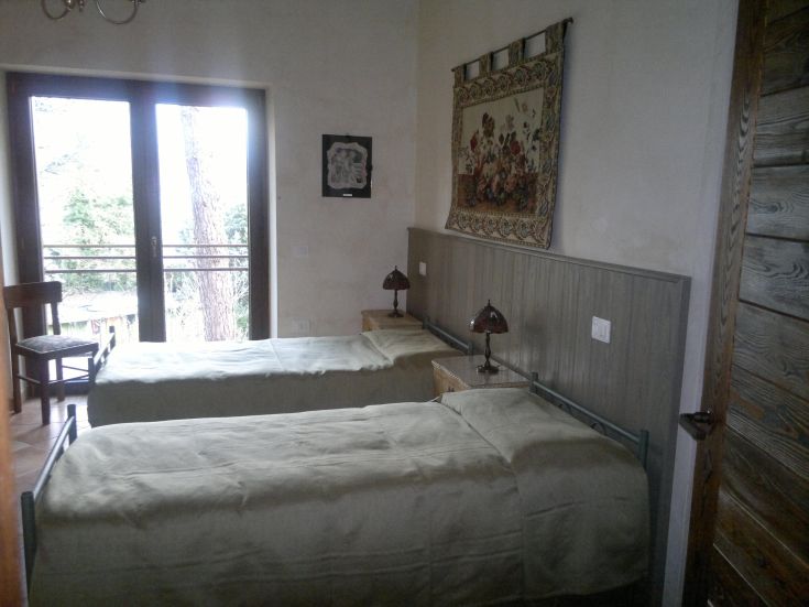 Camera accogliente con due letti singoli, affacciata su un parco verde e con semplici decorazioni.