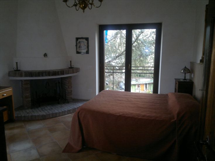 Camera ampia con panorama sul lago, provvista di camino e mobili in legno.