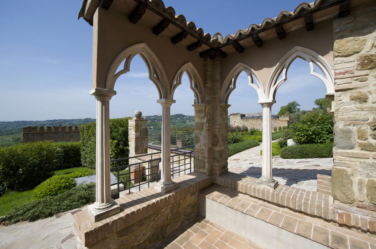 Scène de la pergola au Château de Monterone, entourée d'arbres et de plantes verdoyantes.