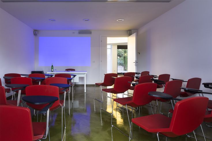 Ambiente ampio e ben illuminato, arredato con sedie rosse, ideale per riunioni e presentazioni.