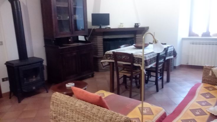 Soggiorno semplice con camino, tavolo e divano, adatto a momenti di convivialità in un appartamento luminoso.