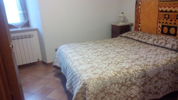 Camera luminosa con letto matrimoniale e arredi semplici, caratterizzata da decorazioni dai toni vivaci.