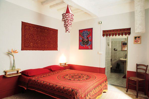 Camera semplice con decorazioni rosse e alcuni dettagli etnici, adatta per un soggiorno tranquillo.