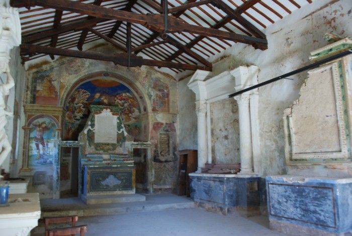 Interno di una chiesa con affreschi, colonne e dettagli architettonici.