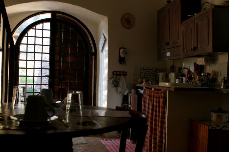 Interno di una cucina confortevole con ampie finestre e dettagli semplici, ideale per momenti conviviali.