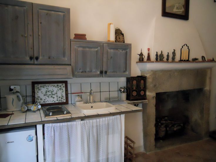 Cucina in stile rustico, dotata di camino, lavello e piastrelle bianche che creano un ambiente accogliente.