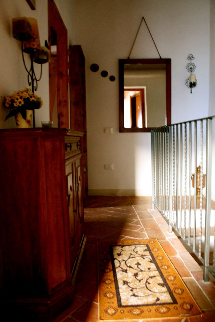 Ingresso semplice con elementi in legno e uno specchio che diffonde la luce.