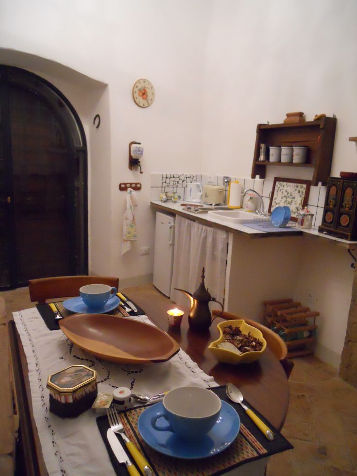Cucina ampia e luminosa con un tavolo apparecchiato e utensili disposti in modo pratico.