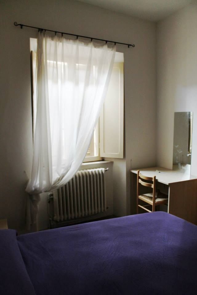 Una camera luminosa e ordinata, dotata di un letto e di una scrivania funzionale.