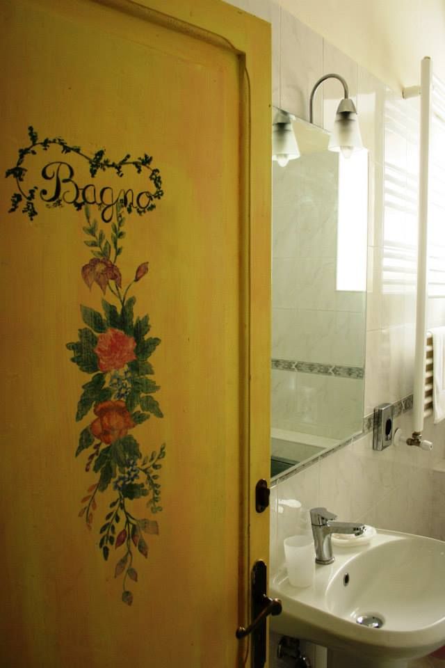 Una porta gialla con decorazioni floreali che immette in un bagno moderno e ben illuminato.