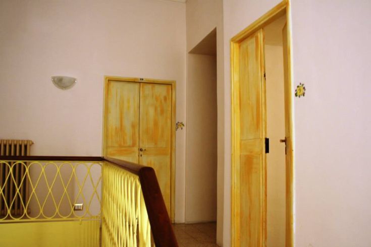 Corridoio con porte gialle e decorazioni semplici, che crea un ambiente piacevole e luminoso.