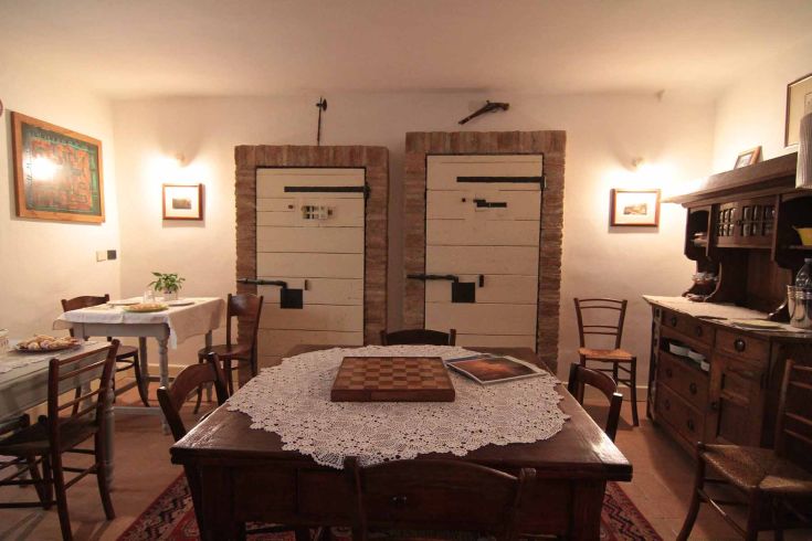 Cozy dining room in a historic building, featuring wooden doors and simple furnishings.