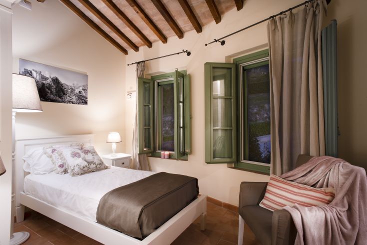 Simple room with twin beds, green windows, and a tranquil atmosphere.