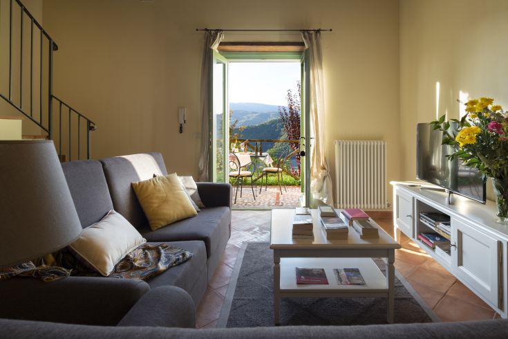 Un tranquillo soggiorno che si affaccia su un panorama di colline verdi. Adatto per momenti di relax.