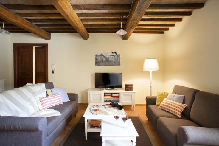 A simple living room with exposed beams, warm lighting, and comfortable furniture.
