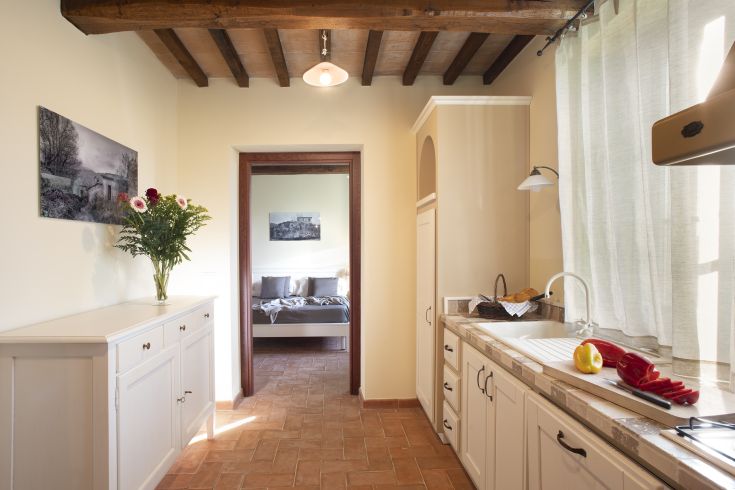 Cucina caratteristica e accogliente che si affaccia su una camera dalle tonalità calde.