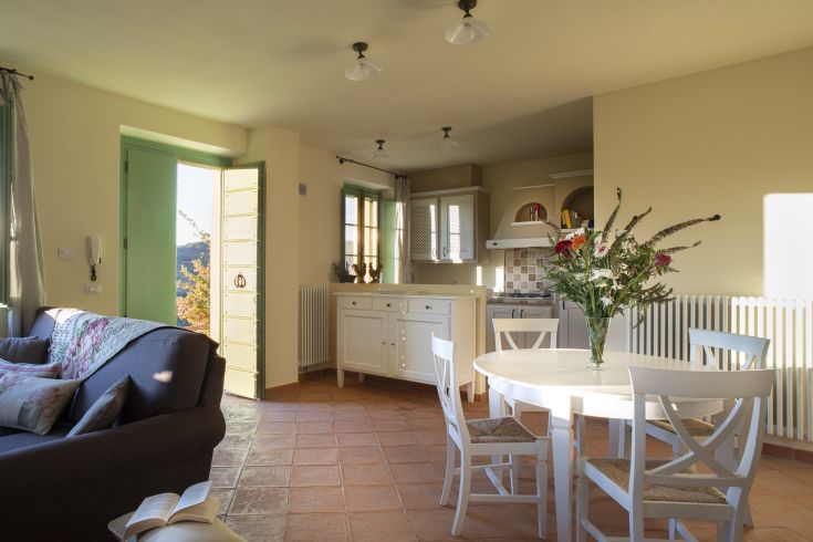 Ambiente luminoso e accogliente che unisce cucina e soggiorno, arredato in modo semplice e pratico.