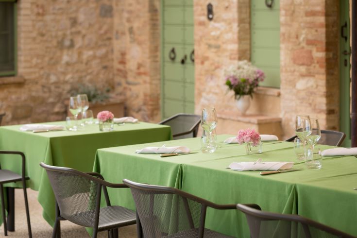 Ambiente tranquillo con tavoli semplici immersi nella natura di un ristorante all'aperto.