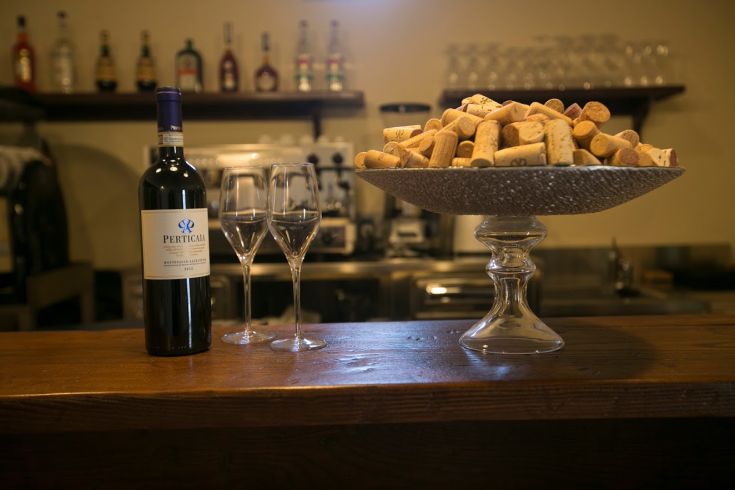 Una bottiglia di vino e due bicchieri su un tavolo, con tappi di sughero sparsi.