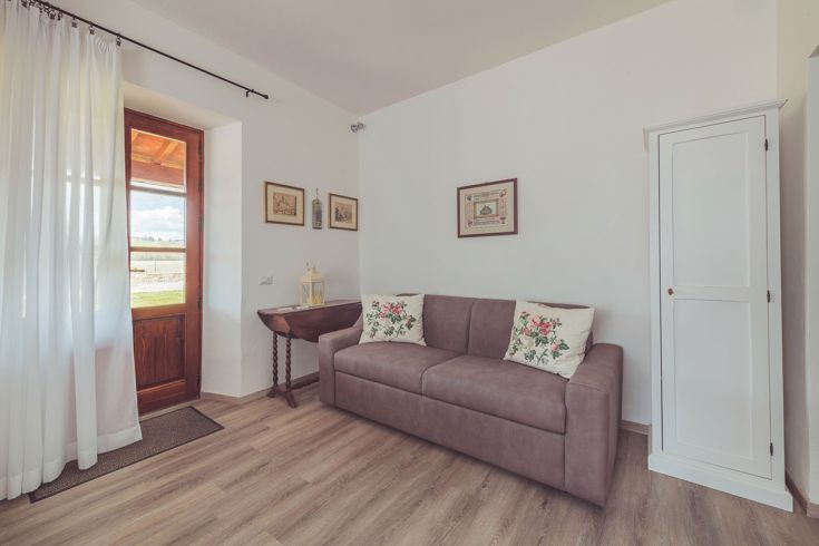 Ambiente confortevole e ben illuminato, dotato di un divano e arredi in stile rustico.