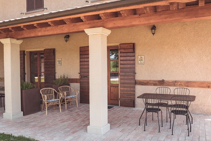 Spazio esterno confortevole con arredi in rattan e un tavolo, perfetto per momenti di relax.