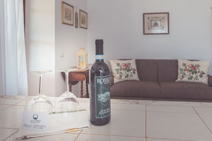 Un ambiente confortevole con vino rosso e bicchieri, perfetto per momenti di tranquillità e relax.