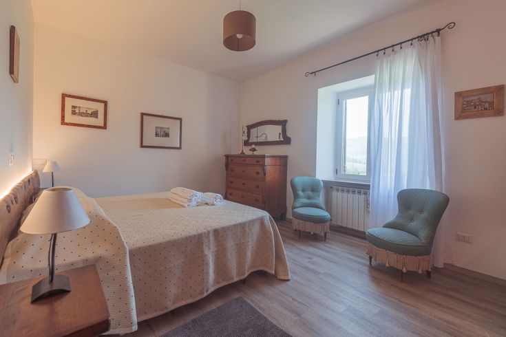 Camera confortevole con letto matrimoniale, arredamento tradizionale e illuminazione naturale.