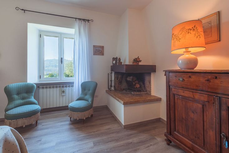 Ambiente confortevole con poltrone e camino, affacciato sulle colline umbre.