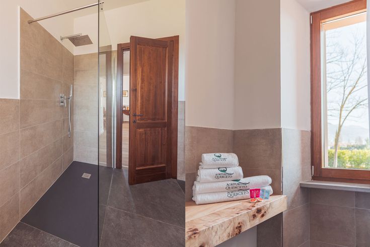 Un bagno moderno dotato di una doccia walk-in, con arredi in pietra e una finestra che illumina l'ambiente.