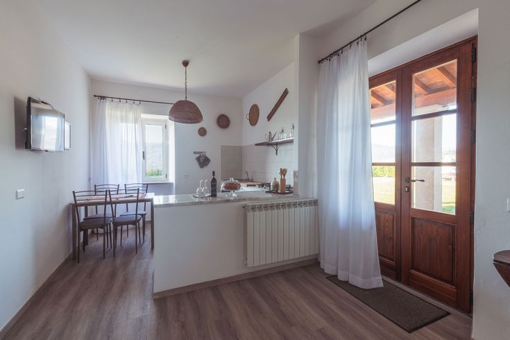 Cucina spaziosa e accogliente, arredata con dettagli rustici e collegata a un giardino esterno.