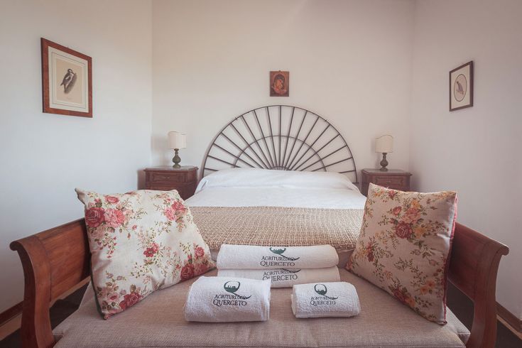 Camera semplice con letto matrimoniale e decorazioni floreali. Ideale per un soggiorno tranquillo.