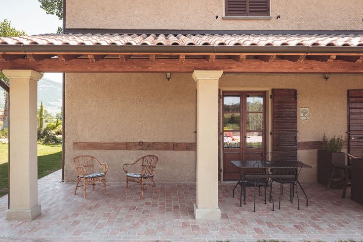 Un'area all'aperto di un agriturismo, attrezzata con sedie in vimini e un tavolo. Un ambiente rilassato nel verde.